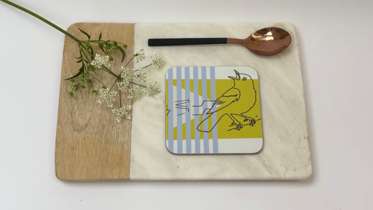 Coaster with a design on a marble surface with a wooden board and spoon.