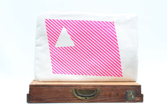 White leptop sleeve with pink diagonal stripes and a white triangle on a wooden surface.