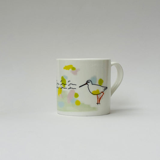 White mug with a colorful bird illustration on a light gray background