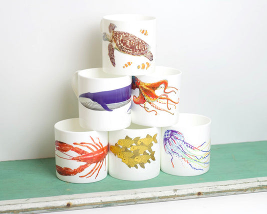 A set of bone china mugs with various underwater animal illustrations, displayed in a stacked arrangement on a shelf.