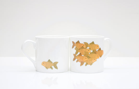 Two white bone china mugs with a goldfish design on a white background.