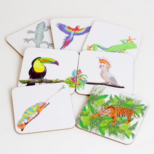 A collection of colorful animal-themed coasters, including designs of a parrot, toucan, cockatoo, tiger, gecko, tree frog, and chameleon, laid out on a white surface.