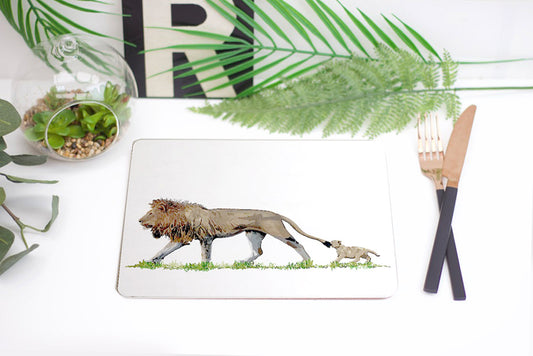 A white placemat with an illustration of a lion and its cub, presented on a table with cutlery and plants in the background.