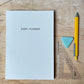 Diary planner, yellow pen, and ruler on a wooden surface