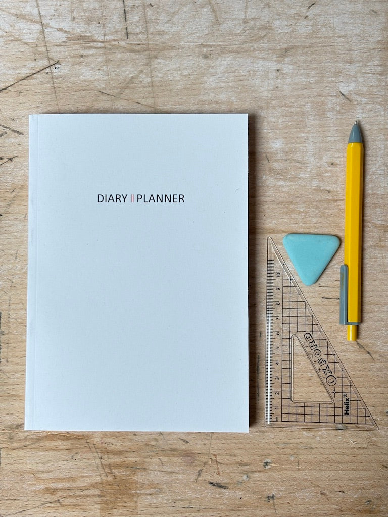 Diary planner, yellow pen, and ruler on a wooden surface