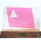 White leptop sleeve with pink diagonal stripes and a white triangle on a wooden surface.