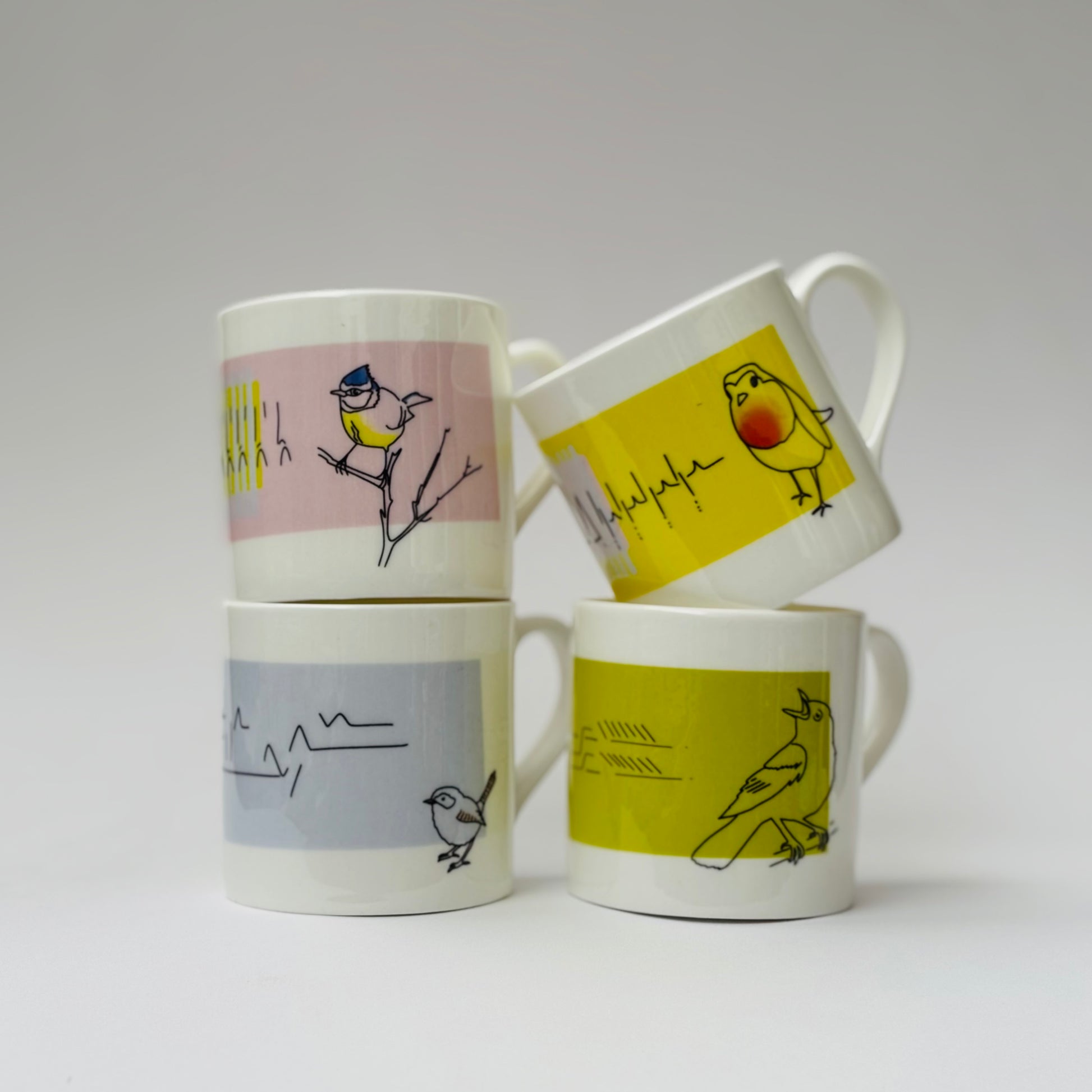 Four mugs with bird illustrations on a white background
