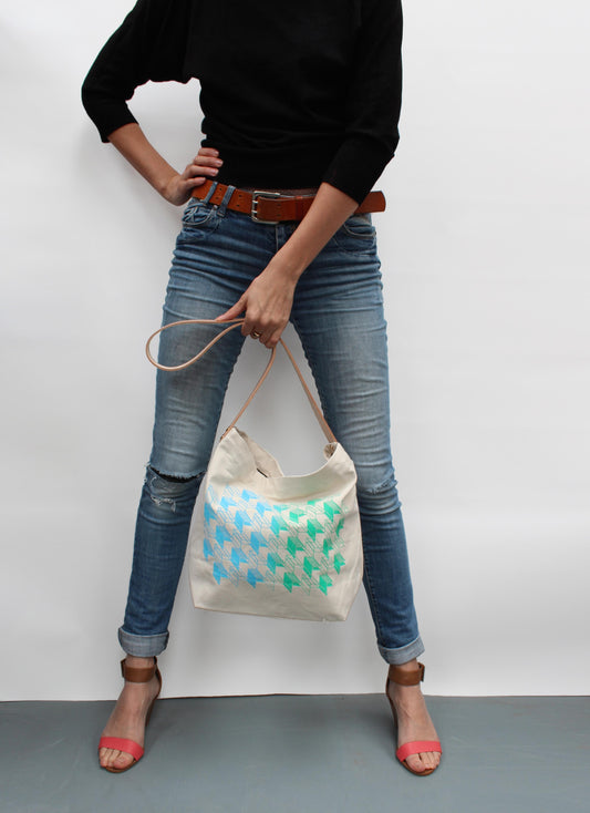 Person holding a tote bag with butterfly design against a plain background
