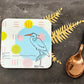Coaster with bird design on a dark surface with a spoon and decorative leaves