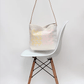 White chair with a light-colored bag hanging on it against a white background