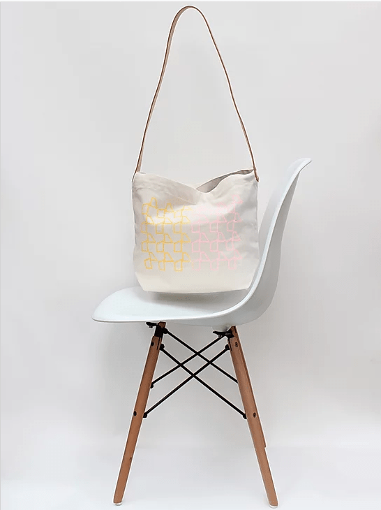 White chair with a light-colored bag hanging on it against a white background