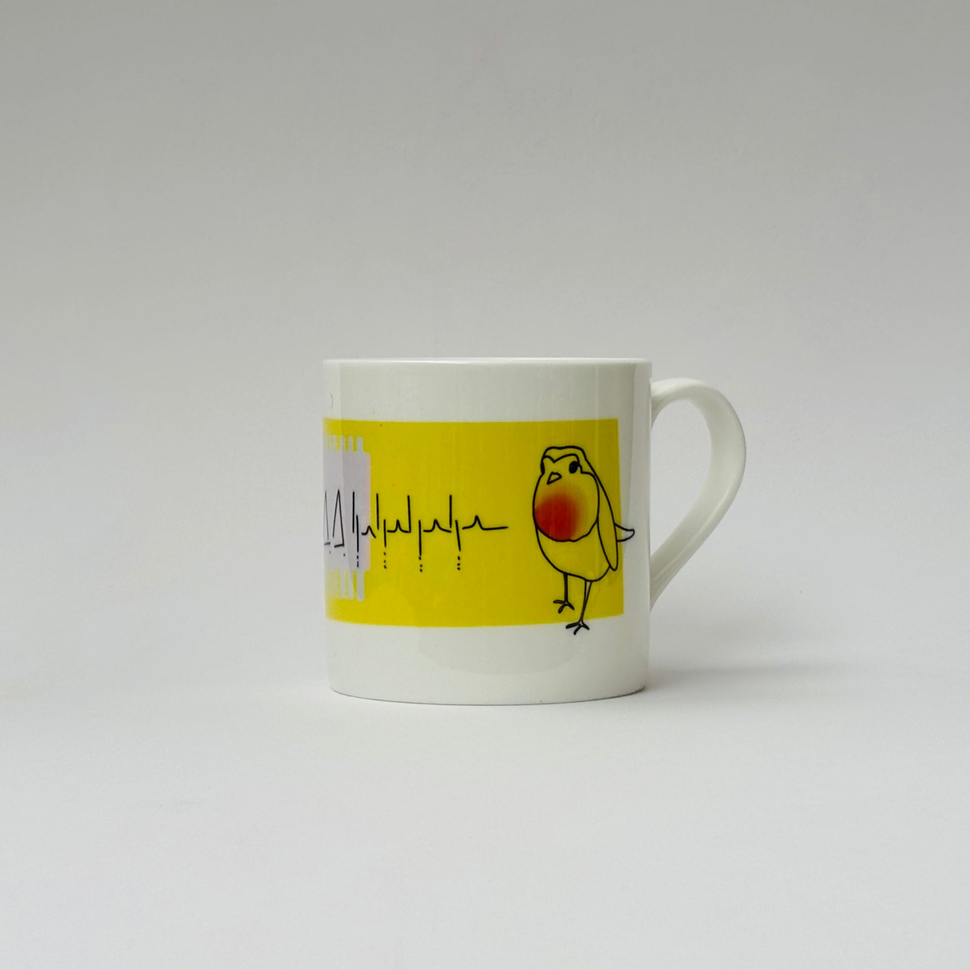 White mug with a yellow label featuring a bird illustration on a white background