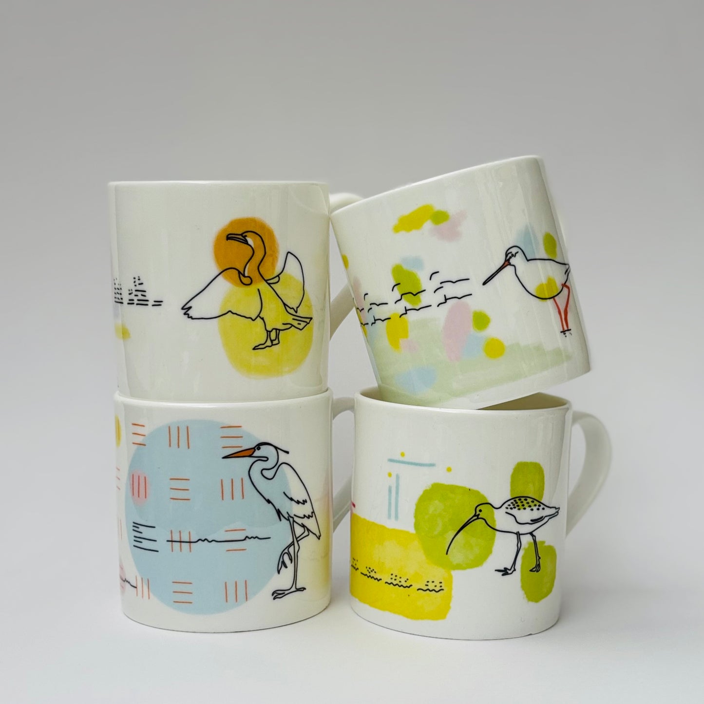 Four ceramic mugs with bird illustrations on a white background