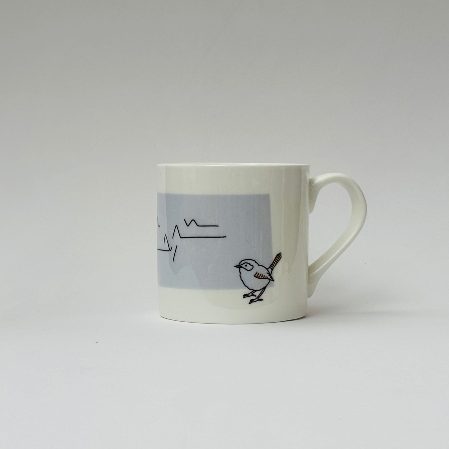 White mug with a bird design on a gray background