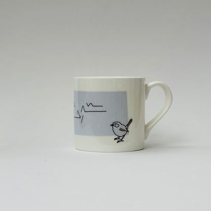 White mug with a bird design on a gray background