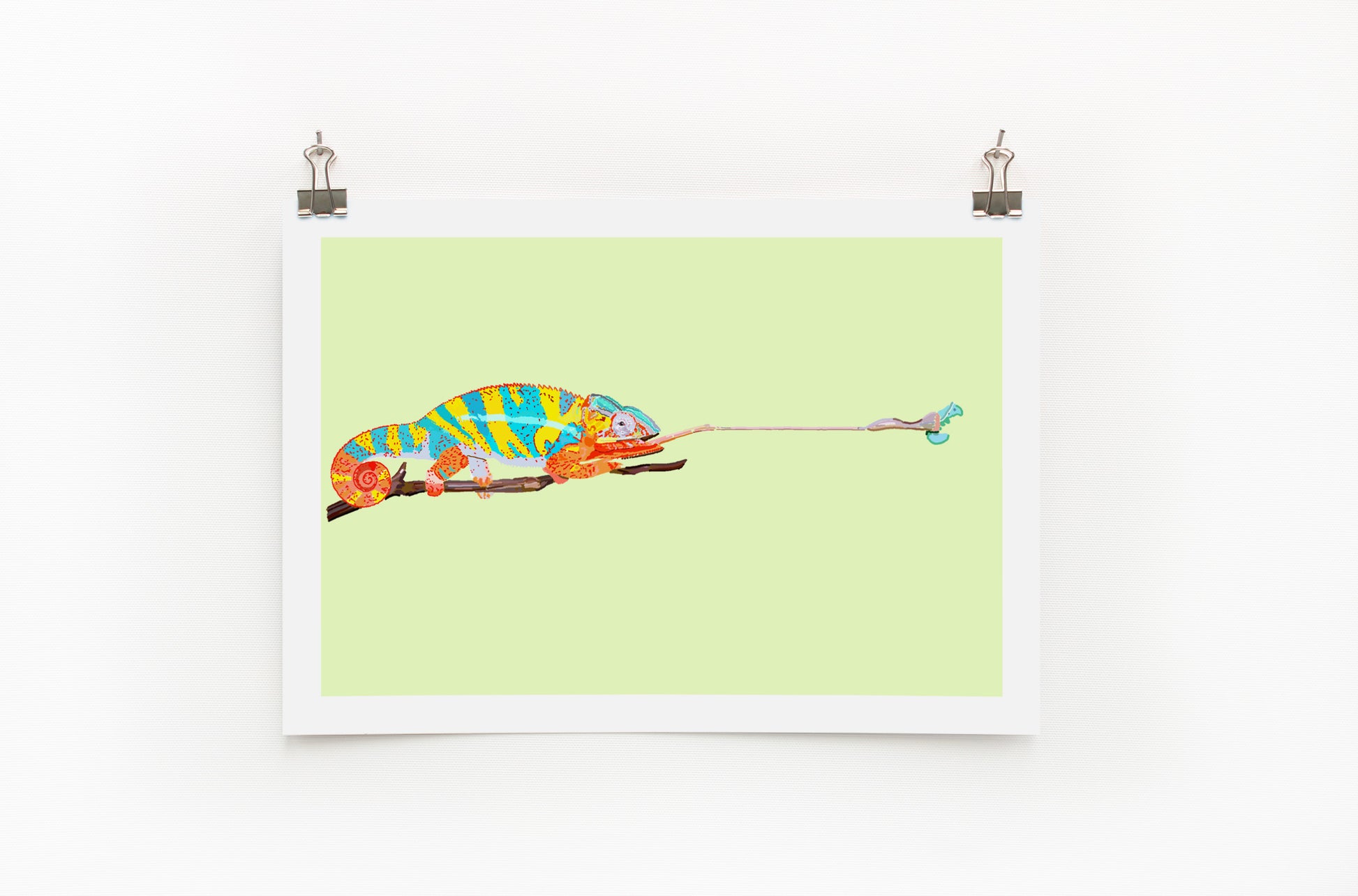 A colorful digital print of a chameleon on a lime background, displayed with clips on a white wall.