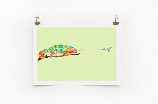 A colorful digital print of a chameleon on a lime background, displayed with clips on a white wall.