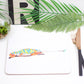 A placemat featuring a colorful illustration of a chameleon with a caterpillar in its mouth.