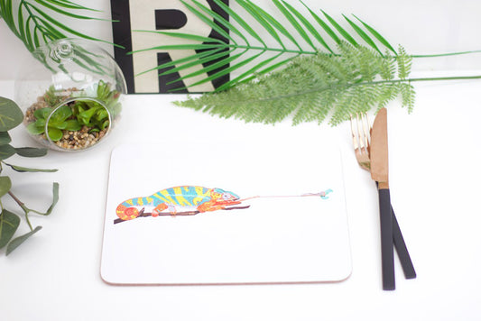 A placemat featuring a colorful illustration of a chameleon with a caterpillar in its mouth.