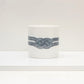 A white bone china mug with a black geometric pattern knot design.