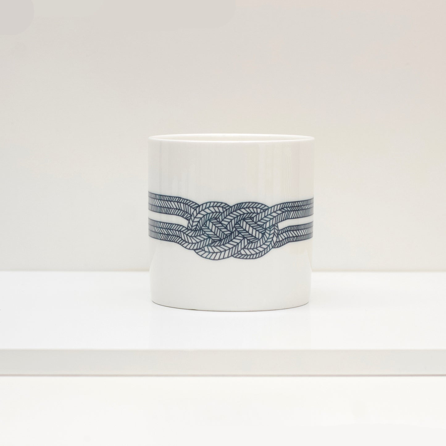A white bone china mug with a black geometric pattern knot design.
