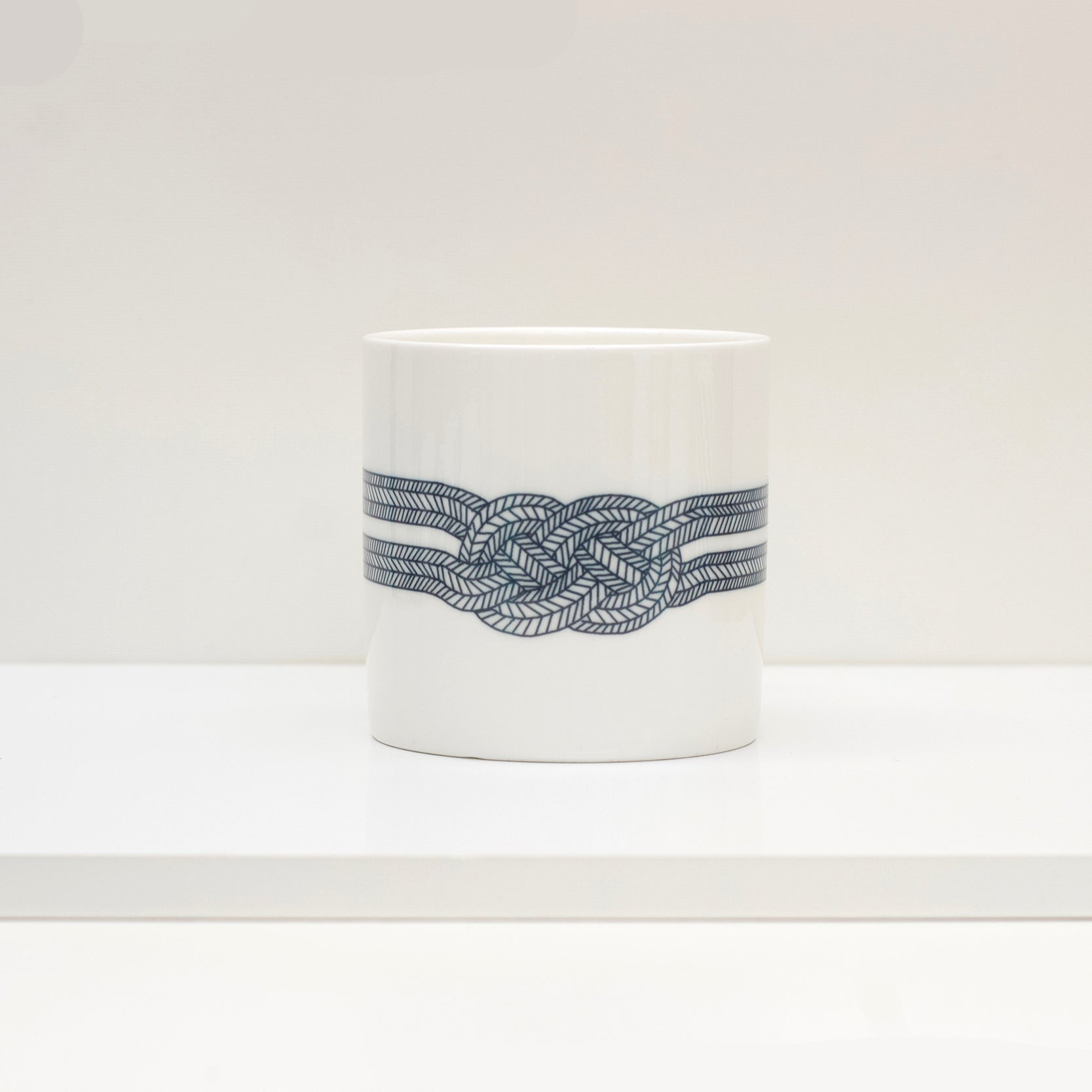 A white bone china mug with a black geometric pattern knot design.