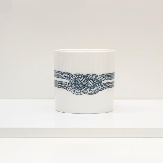 A white bone china mug with a black geometric pattern knot design.