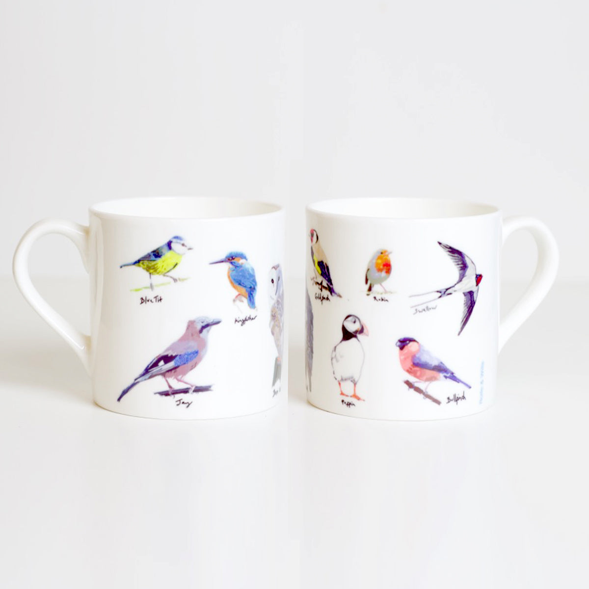 Two white bone china mugs with hand-drawn illustrations of various birds.