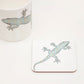 A square coaster with a design of a gecko climbing across it.