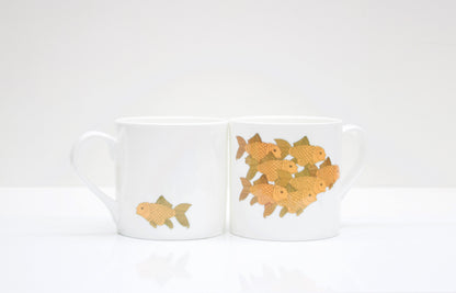 Two white bone china mugs with a goldfish design on a white background.