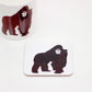 A coaster with an illustration of a gorilla, part of the Africa Collection. The coaster is white with a black gorilla on it.