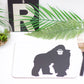 A placemat with a gorilla in the center, placed on a table with cutlery on the right and a green plant in the background.