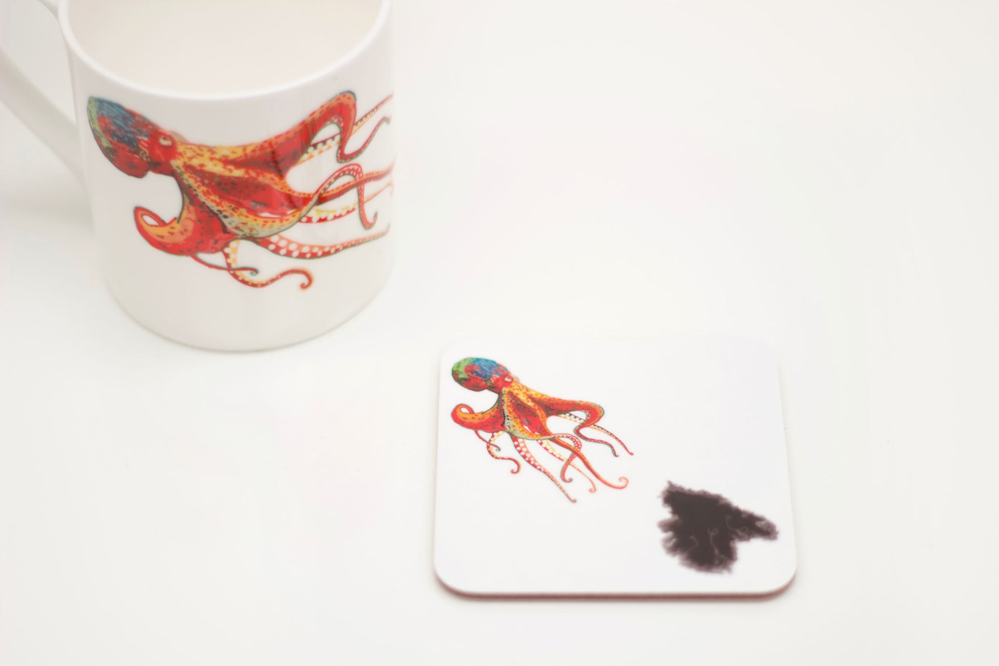 A white coaster with an illustration of an octopus squirting ink, accompanied by an octopus design Bone China Mug