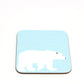 A square-shaped, blue hardboard coaster with a polar bear design.