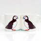 Two bone china mugs puffin designs, one mug showing the front side with the puffin, and the other mug showing the back side. Both mugs have a white color scheme and a reflective surface.