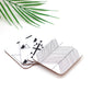 A set of 4 square coasters with a geometric symbol design, placed on a white surface with a green leaves in the background.
