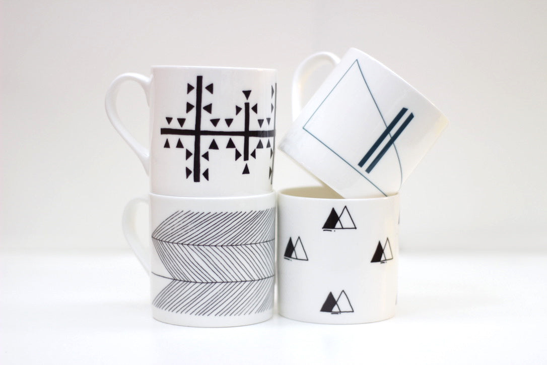A set of four bone china mugs with different patterns, including geometric and abstract designs, from the Symbol Collection.
