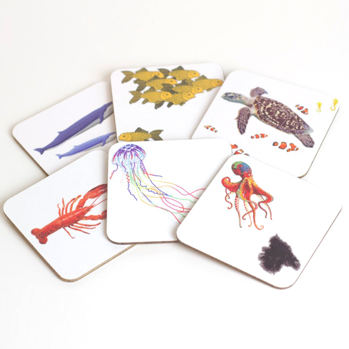 A set of six coasters, each featuring a colorful illustration of various underwater animals, such as jellyfish, an octopus, a blue whale with a calf, a shoal of goldfish, a lobster, and a turtle with a clownfish.