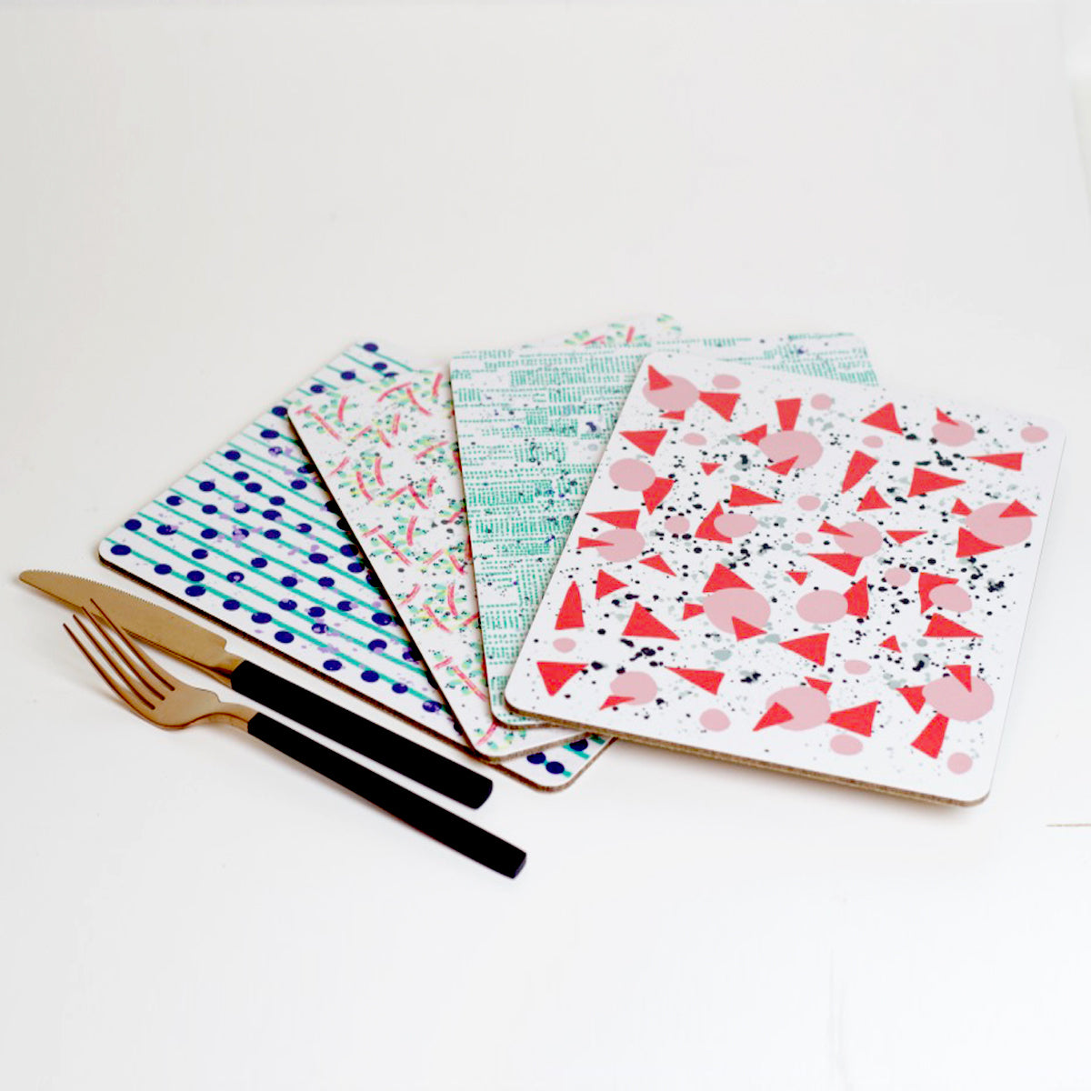 A set of four placemats with various sound-related patterns including geometric and abstract designs, displayed on a white background with a fork and knife to the side.