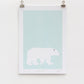A digital print featuring a lone polar bear on a light blue background, mounted on a wall.