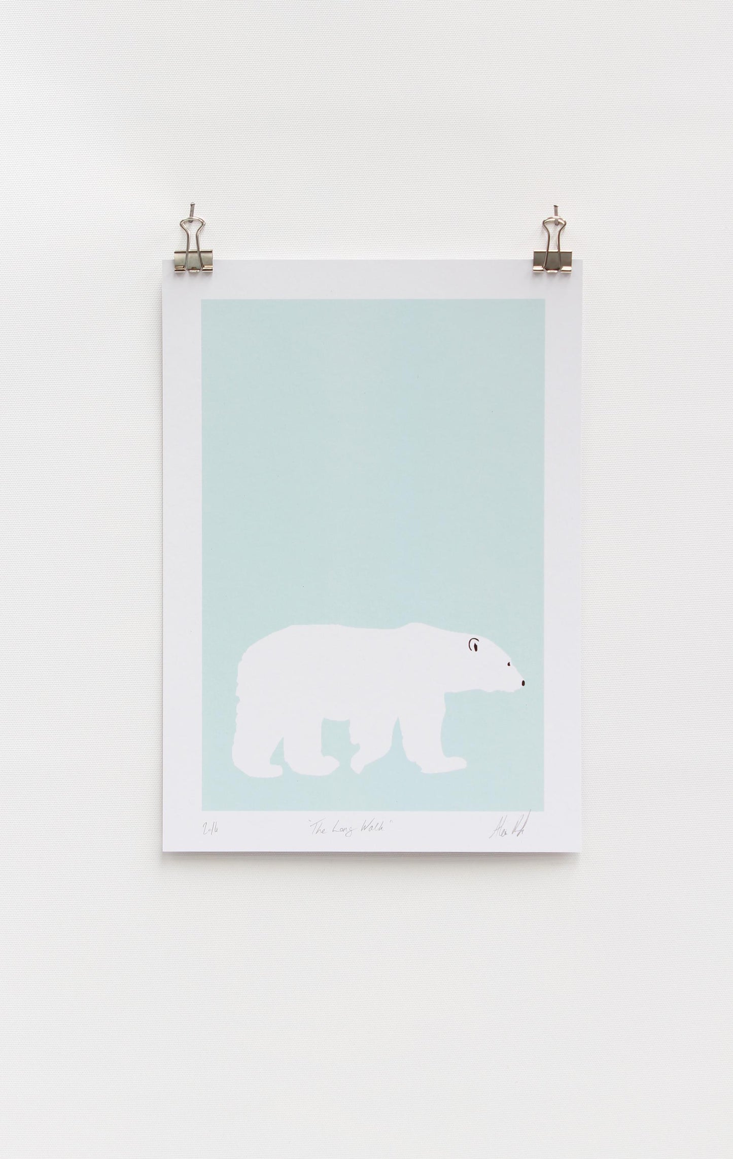 A digital print featuring a lone polar bear on a light blue background, mounted on a wall.