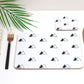 A placemat with a geometric mountain symbol pattern in black and white, displayed on a table with a fork, knife, napkin and matching coaster.