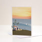 A greetings card with an illustration of a VW campervan and a sunset beach scene.