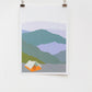 A digital print of a tent in a mountainous landscape, framed and displayed on a white wall using two clip hinges.