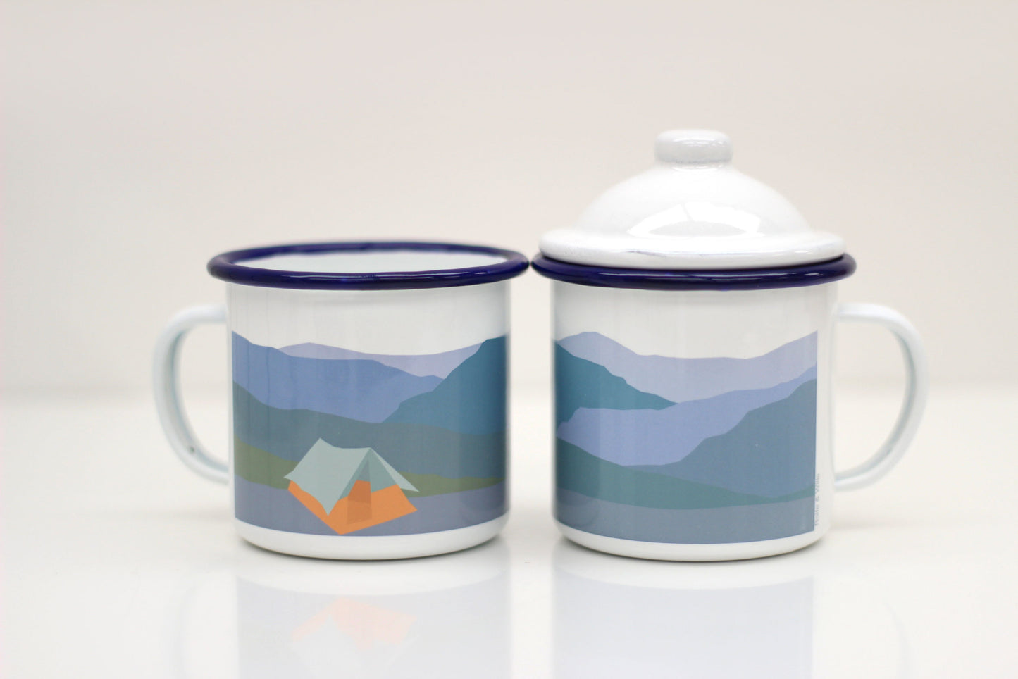 Two enamel mugs with lids, they have a tent design.