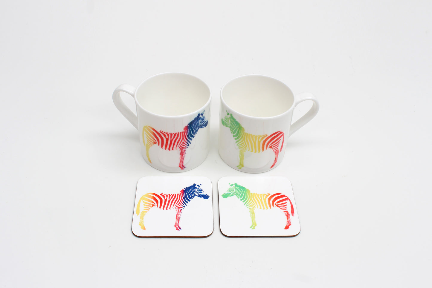 Two square coasters with a multicolored zebra pattern on a white background, displayed on a white surface.